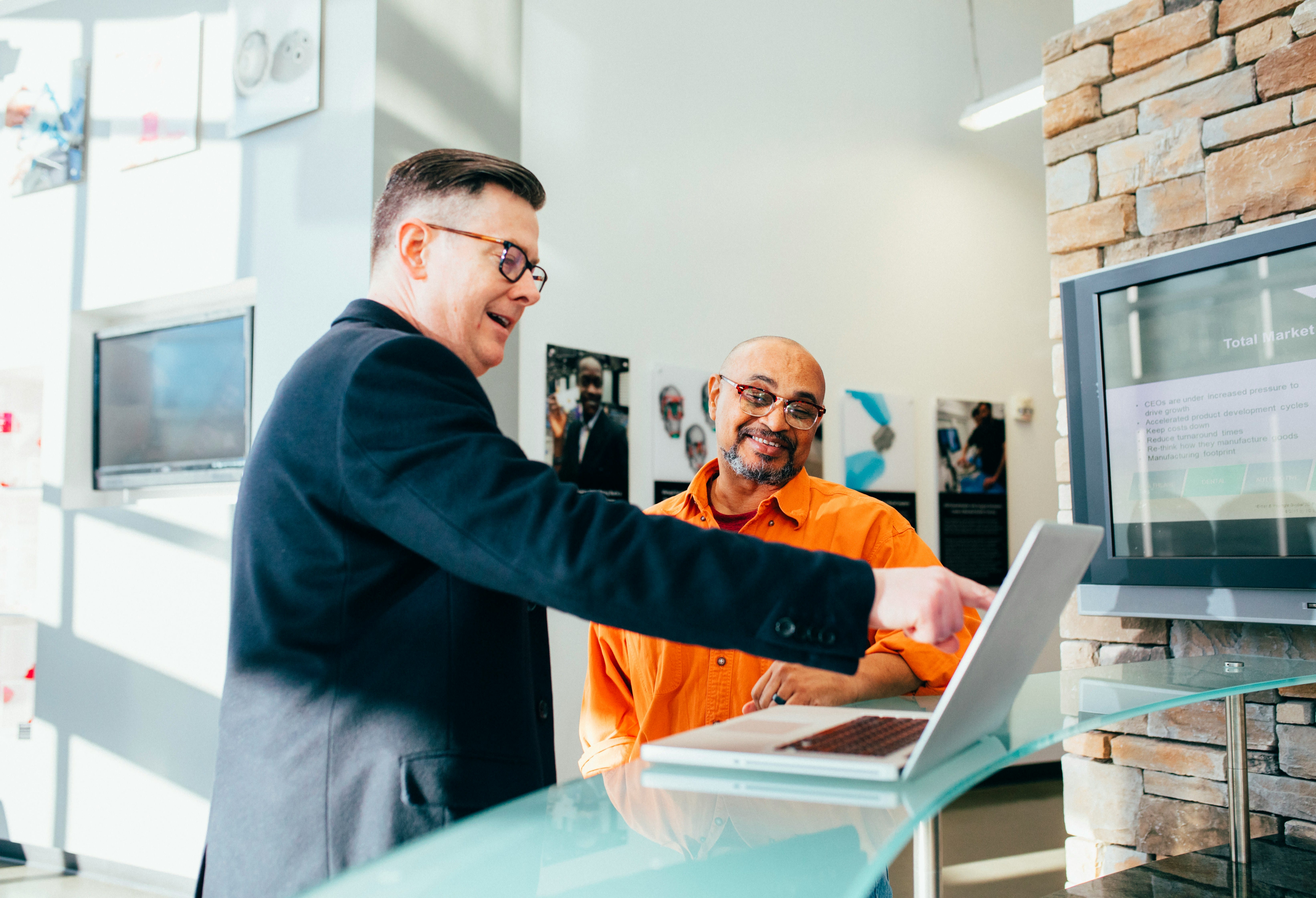 Two men discussing over a laptop in an office.