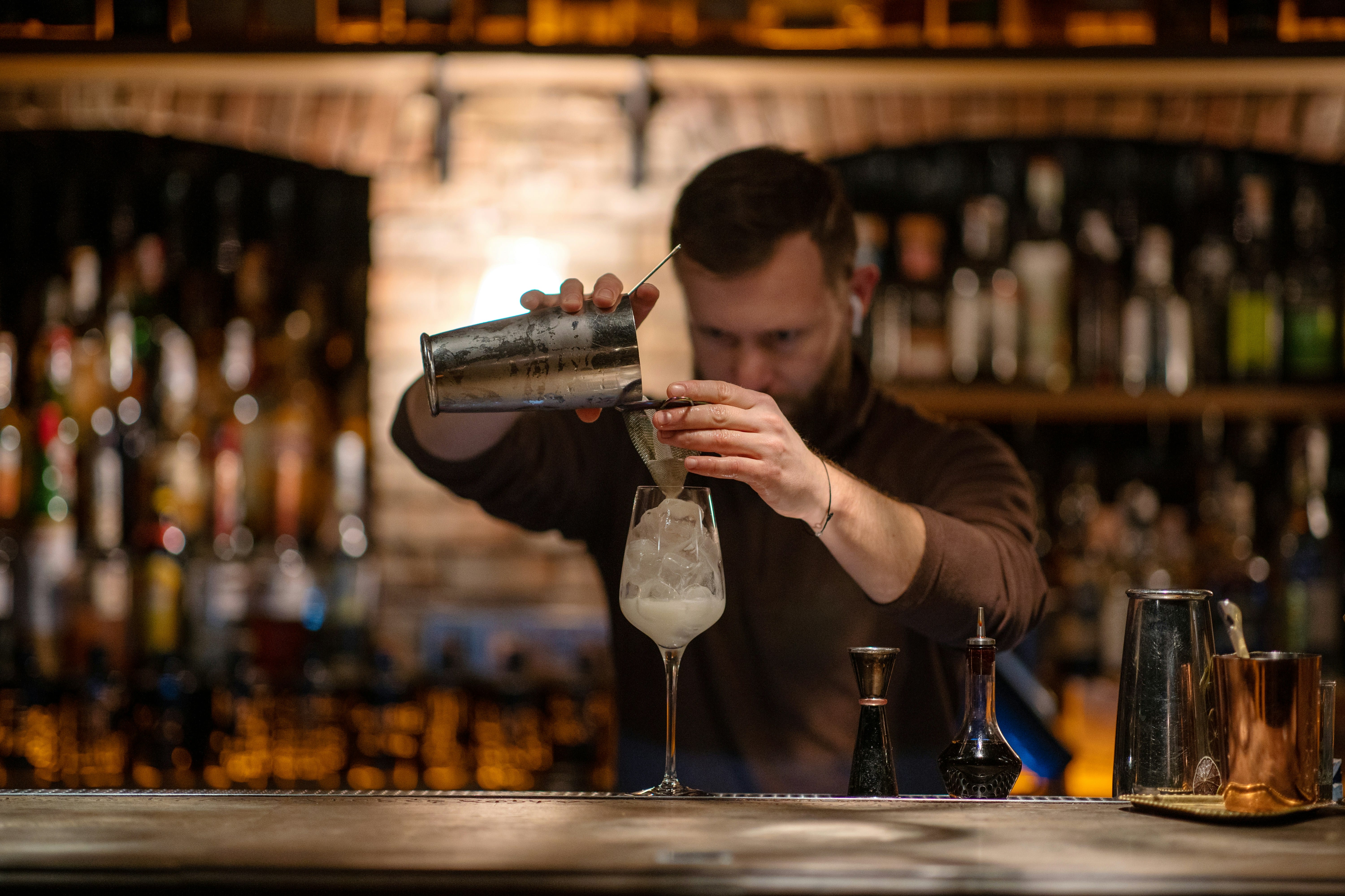 Bartender pouring a cocktail over ice